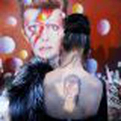 A woman with a Ziggy Stardust tattoo visits a mural of David Bowie in Brixton, south London
