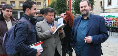 Julio García Llopis firma un libro a un lector, junto a Juan Bas (a la derecha) en el 'bookcrossing' organizado por Federiko Ezkerra.
