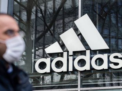 Logotipo de Adidas reflejado en una de sus tiendas. Adidas gana 31 millones de euros hasta marzo, un 95,1 % menos que un año antes. 