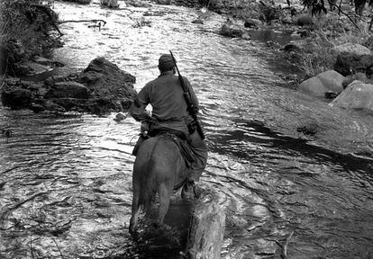 El guerrillero Fidel Castro, fotografiado en Sierra Mestra cuando cruzaba el río Yara a lomos de un caballo y con su arma a la espalda. La imagen formaba parte de la exposición 'Cien miradas de Enrique Meneses'.