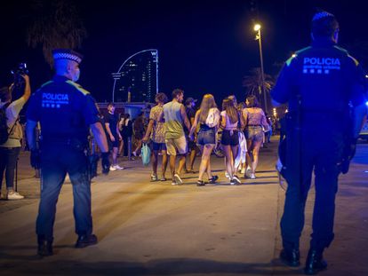 Una pareja de policías desaloja a un grupo de personas que permanecía en la calle tras el toque de queda en Barcelona.
