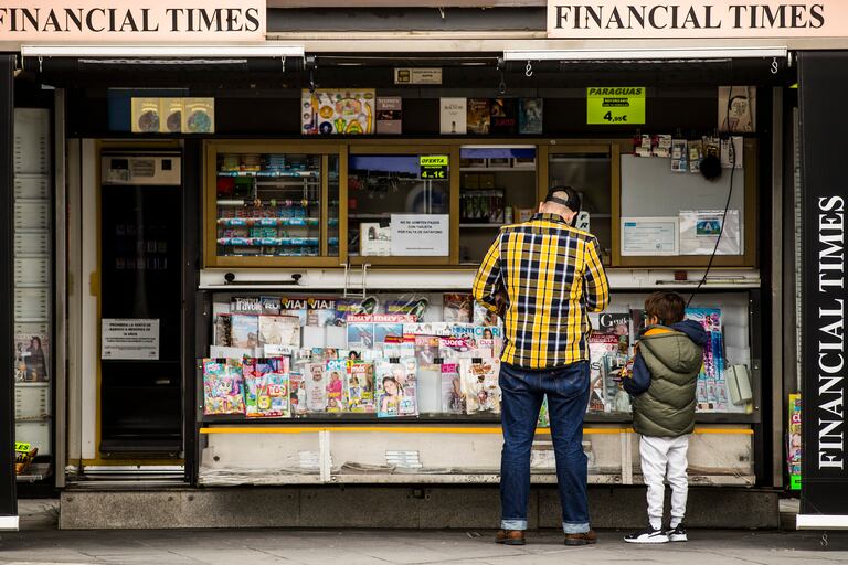 Un padre, con su hijo, en un kiosco de prensa en las inmediaciones del hospital de La Paz de Madrid.