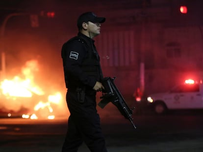 Police officers stand at a scene where a vehicle has been set alight by members of the Jalisco New Generation Cartel (CJNG) following the detention of one of its leaders by Mexican federal forces, in Zapopan, in Jalisco state, Mexico August 9, 2022. REUTERS/Fernando Carranza