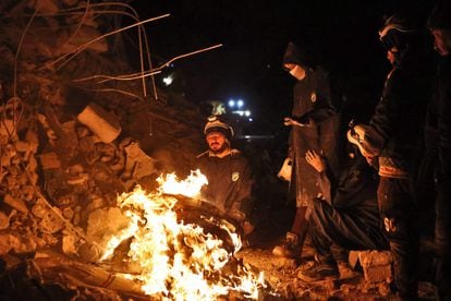 Trabajadores de rescate se calientan en una hoguera en la localidad siria de Sarmada. 