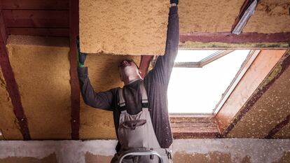 Un trabajador coloca aislamiento en el techo.