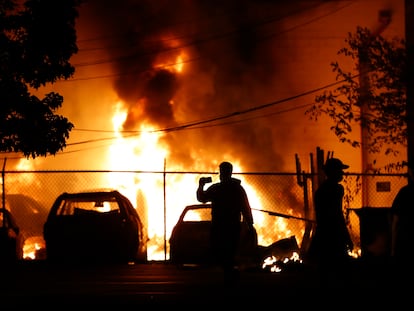 Un hombre mira el fuego de un vehículo en Minneapolis, este viernes.