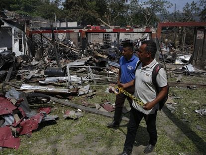 Dos hombres caminan junto a una vivienda destruida por un ataque con carro bomba, en Timba (Colombia), este miércoles.