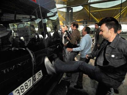 La llegada de una furgoneta con pasajeros desata la ira de algunos taxistas que la emprenden a golpes con el vehículo.