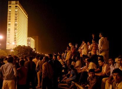 Decenas de personas observan el rescate de rehenes del hotel Oberoi de Bombay, atacado por los terroristas, donde se iba a alojar la presidenta.