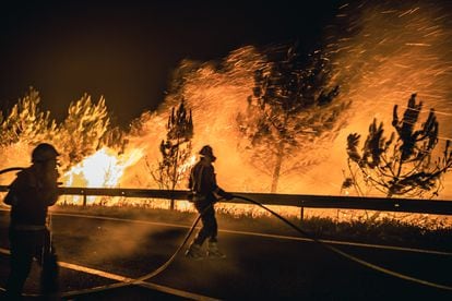 Operarios de las Brigadas de Refuerzo de Incendios Forestales (BRIF) luchan contra las llamas en la madrugada de este sábado para extinguir el incendio declarado en el día anterior en la parroquia de Boiro.