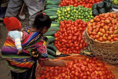 Una mujer compra verdura en un mercado en Guatemala.