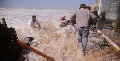 Empleados intentan salvar un chiringuito del temporal en Cádiz.