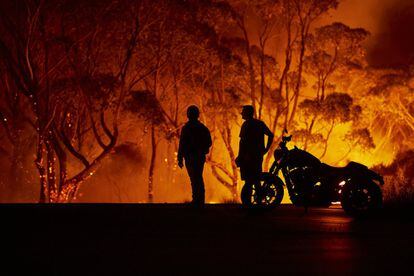 Dos residentes observan las llamas en Lake Tabourie, Australia.
