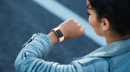 Una usuaria de una pulsera de actividad mira la hora en su Fitbit Charge 2.