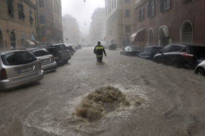 Un bombero trata de caminar en una calle inundada en G&eacute;nova (Italia)