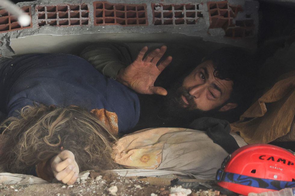 Un hombre yace entre los escombros junto al cadáver de su mujer