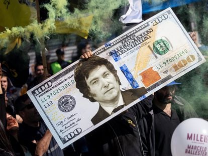 Un seguidor de Javier Milei sostiene la réplica de un billete de un dólar estadounidense con la cara del ultraderechista.