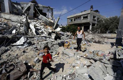 Un hombre y una niña llevan sus pertenencias de vuelta a su hogar destrozado, en la ciudad de Beit Hanun.