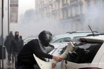 Un manifestante destroza la ventana de un vehículo durante una protesta con motivo de la inauguración oficial de la Exposición Universal de Milán 2015.