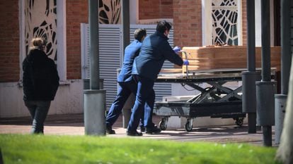 Dos trabajadores trasladan un féretro en el cementerio de La Almudena, en Madrid, el pasado marzo.