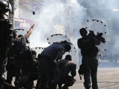 Agentes de polic&iacute;a se protegen y lanzan granadas de gas lacrim&oacute;geno contra los &#039;okupas&#039;.