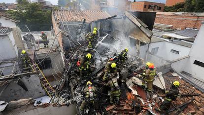 Bomberos trabajan en las casas donde se estrelló la avioneta en Medellín.