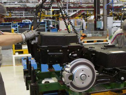 Dos operarios colocan las bater&iacute;as de la furgoneta el&eacute;ctrica Citro&euml;n Berlingo en la cadena de montaje de la planta de PSA.