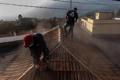 Moduo y Federico limpian la ceniza de un tejado en una casa en El Paso, uno de los municipios más cercanos al volcán.