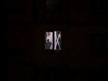 Una mujer retira cinta adhesiva colocada en una ventana de su piso, iluminado por generadores, ayer en Kiev.