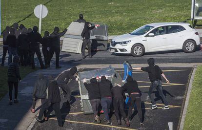 Encapuchados arrastran contenedores en el campus de Leioa (Bizkaia) de la UPV.