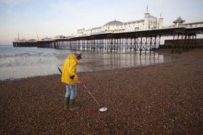 Un hombre con un detector de metales junto al muelle de Brighton (Reino Unido).