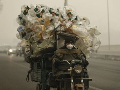Un motorista conduce su motocarro por Shangháilleva repleto de botellas de plástico para ser recicladas.