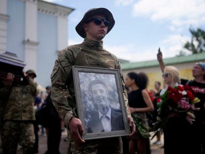 Un soldado ucranio sostiene un retrato del activista Roman Ratushni, muerto en el frente oriental de la guerra, durante su entierro el sábado en Kiev.