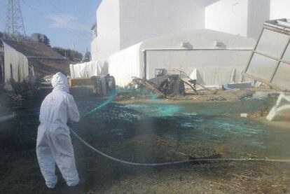 Un técnico esparce resina sintética en el suelo de Fukushima.
