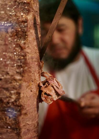 Un empleado de Hasir corta la carne de la brocheta vertical del restaurante, una imagen clásica de este tipo de locales.
