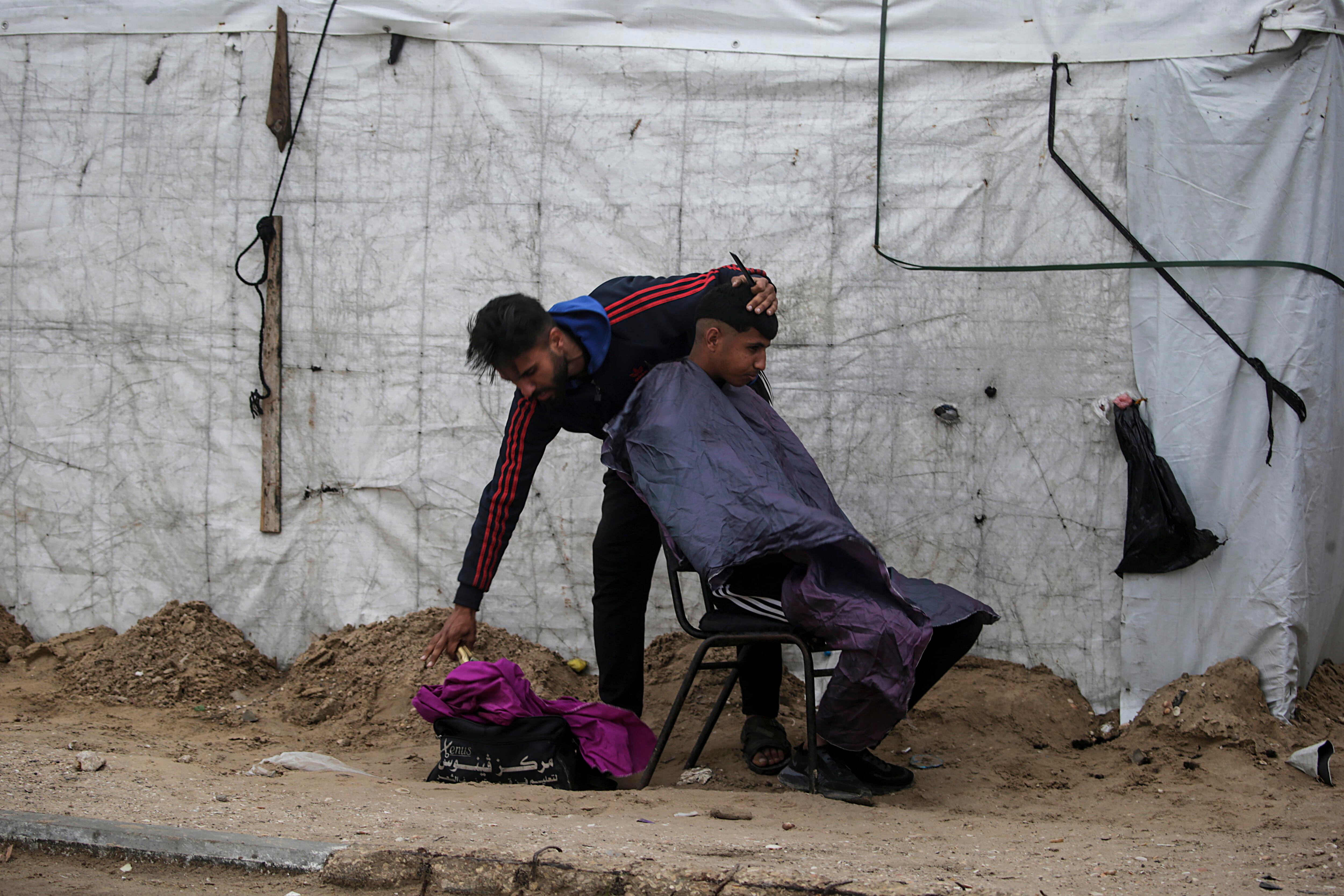 Un refugiado palestino corta el pelo a otro en un campamento en la localidad de Deir al Balah, al sur de la franja de Gaza.