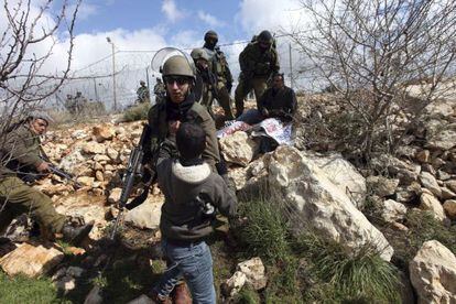 Un soldado israelí empuja a un niño palestino durante los enfrentamientos en Beit Omar, cerca de Hebrón, en Cisjordania, el día 17 de marzo de 2012.