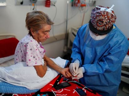 Una médica toma una muestra de sangre a una enferma grave de covid en un hospital a las afueras de Buenos Aires (Argentina).