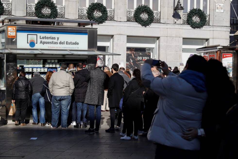 Un gran número de personas espera su torno para adquirir lotería en un kiosko instalado en la Puerta del Sol de Madrid