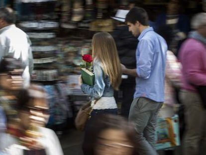 Una parella passeja amb rosa i llibre, durant la diada de Sant Jordi, per un carrer de Barcelona.
