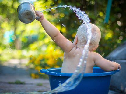 Un bebé juega con el agua en un barreño.