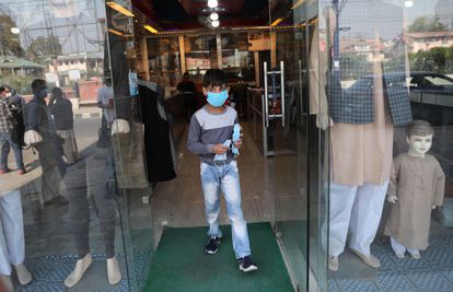 Un niño de Cachemira sale de una tienda después de distribuir mascarillas para prevenir la propagación del coronavirus, en Srinagar, la capital de verano de la Cachemira india.