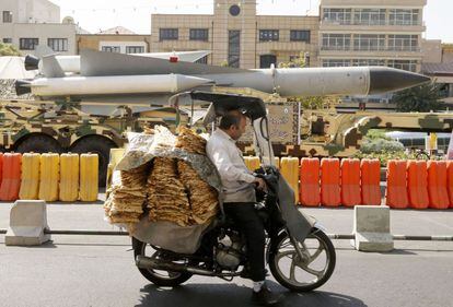 Un hombre pasa con su scooter frente a un misil tierra-aire S-200 en la plaza de Baharestan en Teherán (Irán).