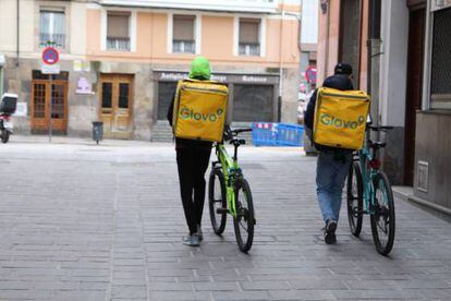 Dos repartidores de Glovo empujan sus bicis por la calle