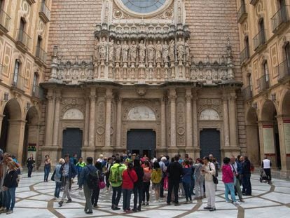 Diversos turistes i feligresos congregats davant de les portes del monestir de Montserrat.