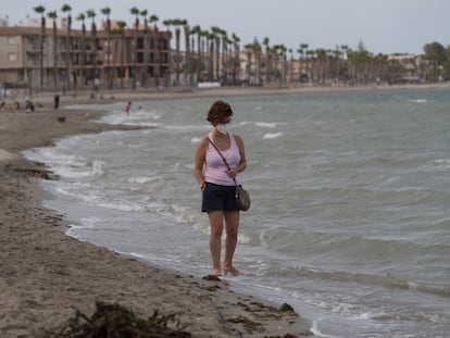 Una vecina de Los Alcázares camina por la orilla del mar Menor.