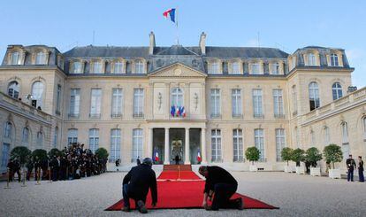 Unos empleados extienden la alfombra roja frente al palacio del Elíseo por la que desfilarán Nicolas Sarkozy y el presidente electo Hollande.