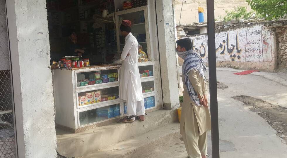 Los vecinos de este pueblo pakistaní guardan la distancia de seguridad en la puerta de una tienda.