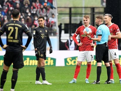 El árbitro Christian Dingert dialoga con sus asistentes por el pinganillo tras detener el encuentro entre el Friburgo y el Bayern.