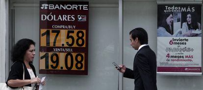 Mexicanos caminan frente a un banco con la cotización del peso mexicano, el pasado junio.